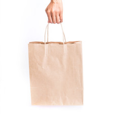 hand holding brown paper shopping bag on white background