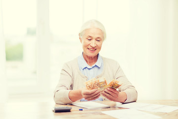 senior woman with money and papers at home