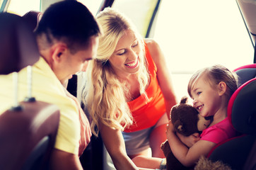 happy parents with little girl in baby car seat