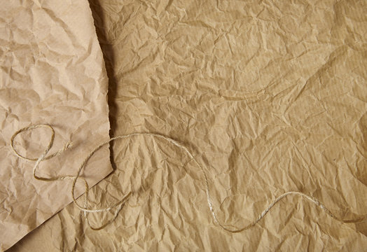 A full page of torn and creased brown parcel paper texture with string