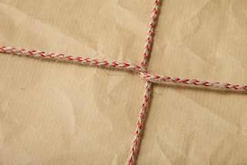 A full page of creased brown package paper texture with red striped string tied around it