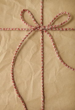 A full page of creased brown parcel paper texture with red string bow tied around it