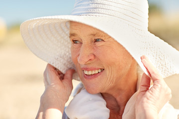 happy senior woman in sun hat on summer beach
