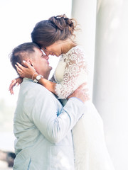 Groom embraces Russian bride on a background of white columns