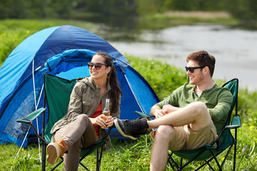 happy couple drinking beer at campsite tent