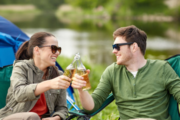 happy couple clinking drinks at campsite tent