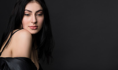 Naklejka premium Portrait of happy smiling beautiful brunnette model woman posing in black lingerie or underwear isolated on black background in studio.