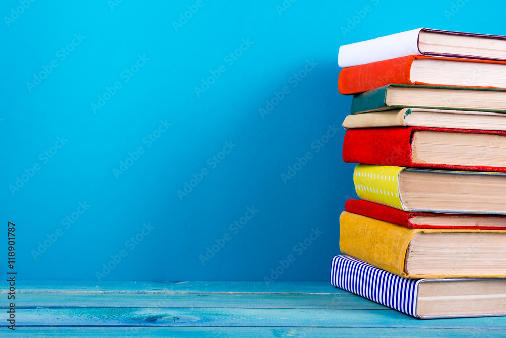 Wall mural Stack of colorful books, grungy blue background, free copy space