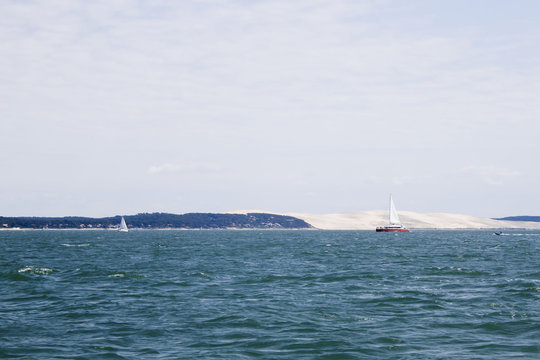 sail boat sailing in front of Pilat dune in France