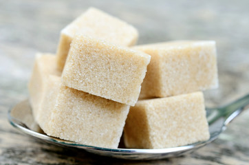 Beige sugar cubes in a silver spoon