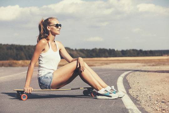 Young woman sitting on skateboard