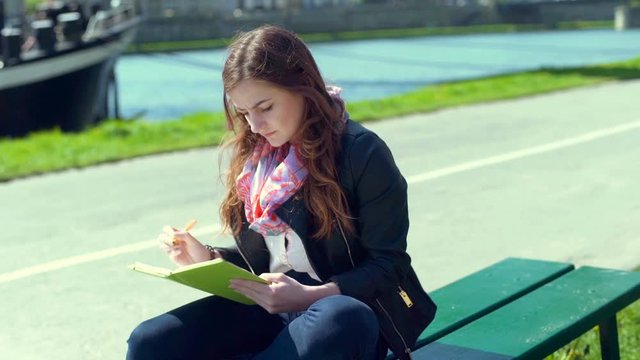 Girl writing something in the notebook and having a headache
