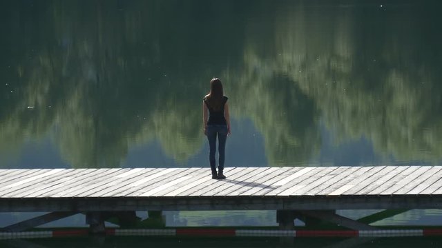 Woman looks at landscape reflecting on the water