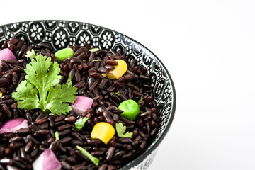 Black rice and vegetables in a bowl isolated on white background

