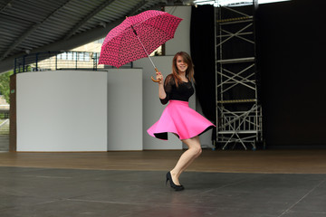 Piękna kobieta tańczy z parasolką na scenie amfiteatru. - obrazy, fototapety, plakaty