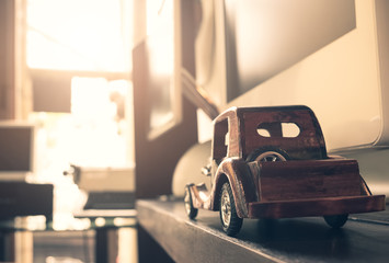 wooden toy car on hardwood balcony next to a window with sun light and vintage tone.