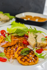 Grilled sweet potatoes and roast turkey with herbs served on white plate.