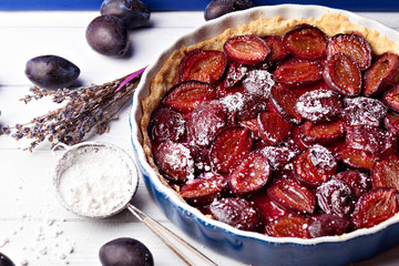 Homemade pie with plums and sieve on the table