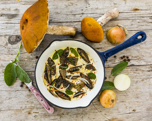 Forest mushrooms fried in a pan on a wooden rustic table.
