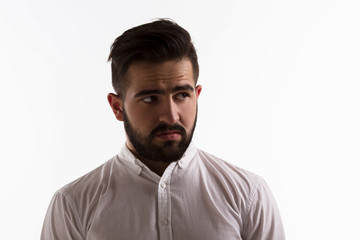 Picture of thoughtful handsome hipster man looking away while posing in studio. Bearded brunette man posing isolated on white background. Hard light concept.