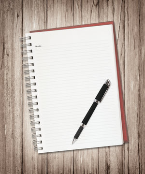 Blank note book with pen on wood background