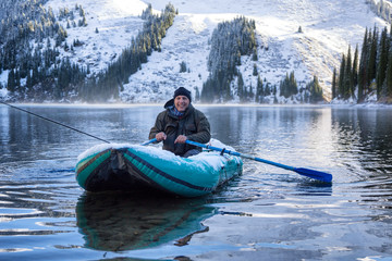 Fototapeta na wymiar Autumn fishing after snowfall on the lake Kolsai, Kazakhstan