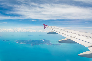 Wing of a plane from window view with Koh Samui in background in Surat Thani, Thailand.