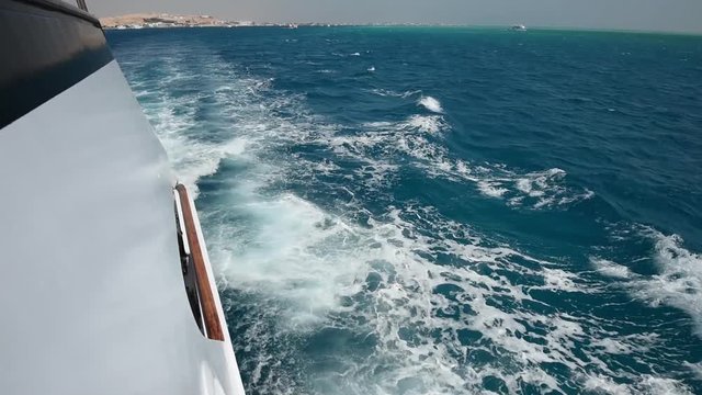 View from side of a large luxury motor boat while sailing across tropical ocean landscape