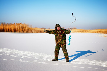 Ice fisherman drill on winter lake  - 118916747