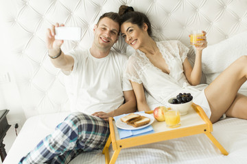 Obraz na płótnie Canvas Couple in bed taking selfie
