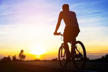 Fototapeta na wymiar silhouette men cycling on road at sunset