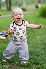 Cute baby boy playing and laughing in the park. Summer is around a lot of greenery  interesting things for crumbs. Kid 1 year