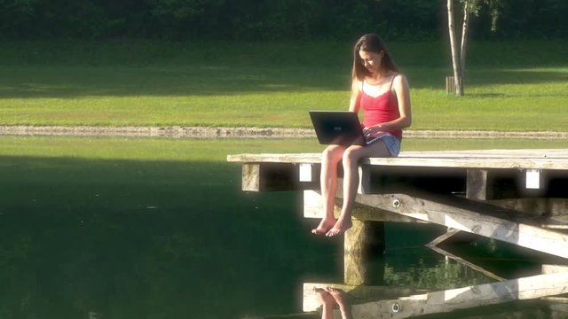 Woman with laptop on vacation on the lake
