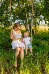 Fototapeta premium Pregnant mom with a boy resting in a meadow.