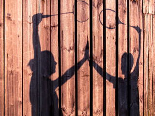 Toned image of silhouettes of men and women holding hands with tennis rackets on the background of old planks of wood