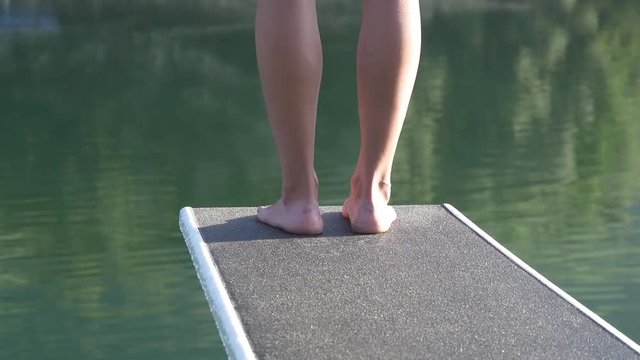 Woman feet on springboard in front of a lake