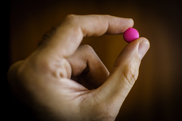 Fingers holding a purple pill