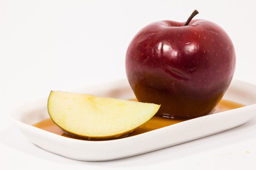 Red apple and red apple slice on white plate with honey isolated on a white background