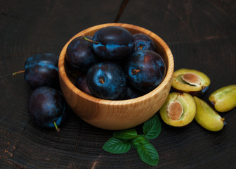 Bowl with  plums with green leaves