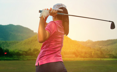 Young women player golf swing shot on course in morning sunrise