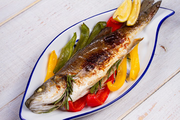 Whole grilled seabuss fish with colorful peppers, lemon and rosemary