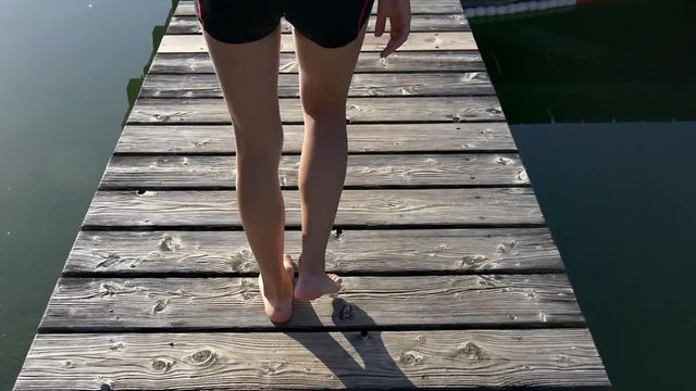 Woman walks on dock and dives into the water