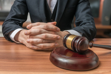 Lawyer has clasped hands and gavel in front. Justice and Law concept.