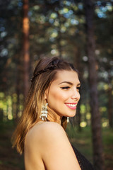 Naklejka premium Beautiful blonde young woman with cute hairstyle and silver earrings outdoors
