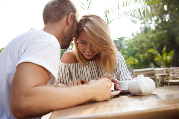 Young beautiful couple speaking, smiling, resting in cafe.