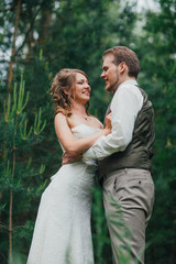 Bride and groom are embracing against the background forest