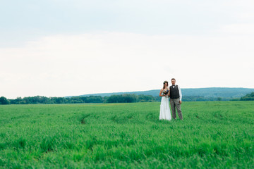 the bride and groom with a bouquet on the green field