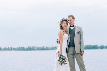 young groom and bride standing hugging on the background of the river