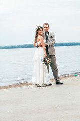 young groom and bride standing hugging on the background of the river