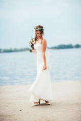 Fototapeta na wymiar young bride with a bouquet of flowers standing on the background the river
